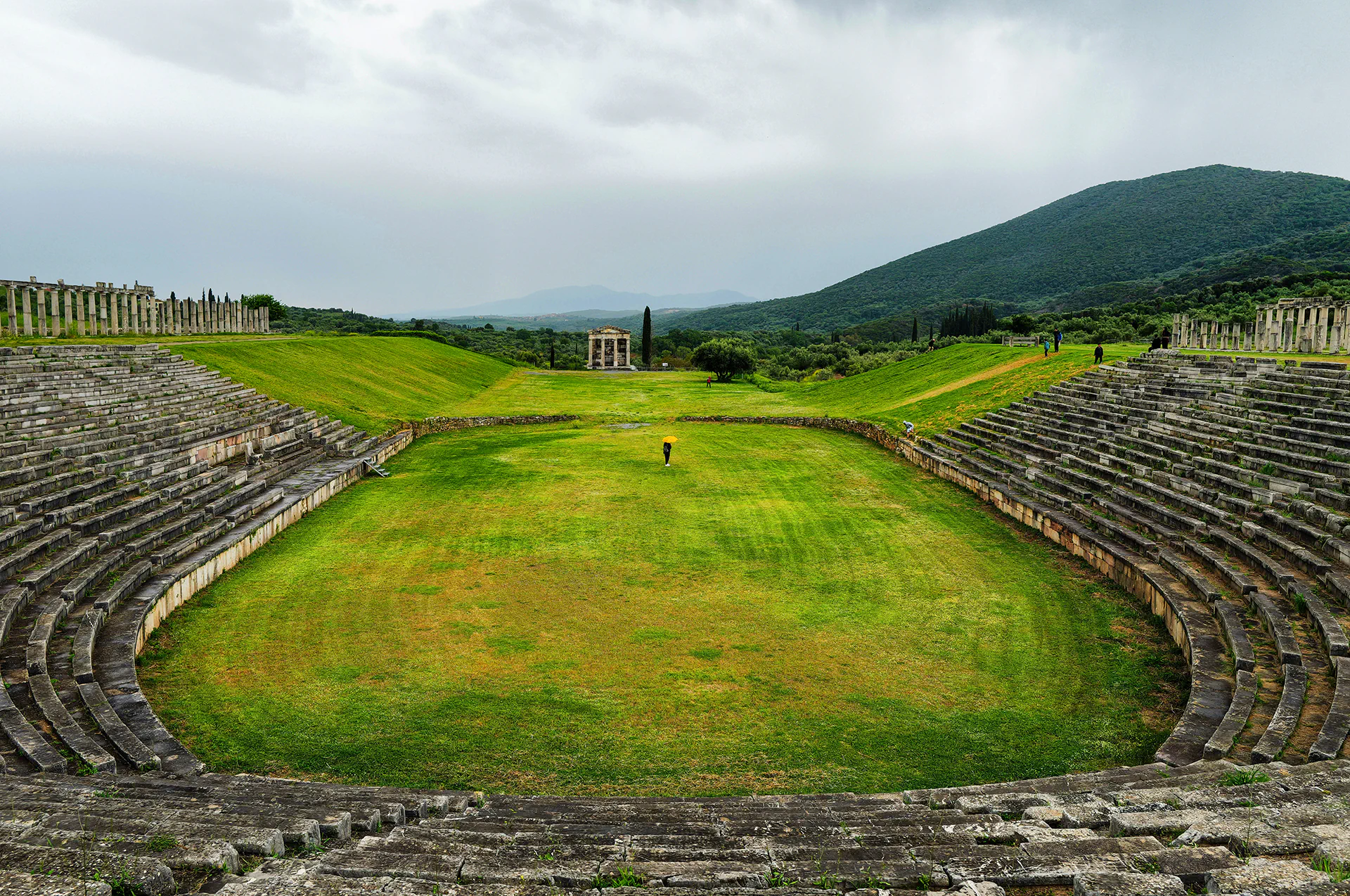 Ruins of Ancient Messene with stone theater and mountain backdrop.
