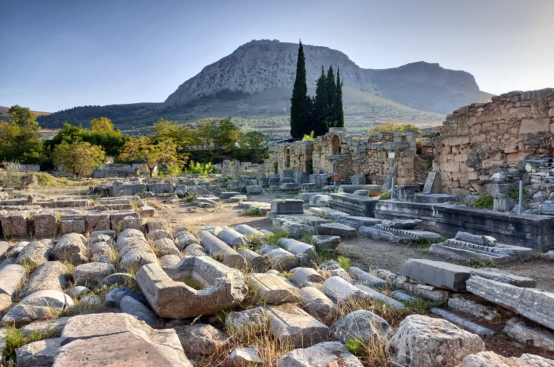 View of archaeological ruins with Acrocorinth in the background.