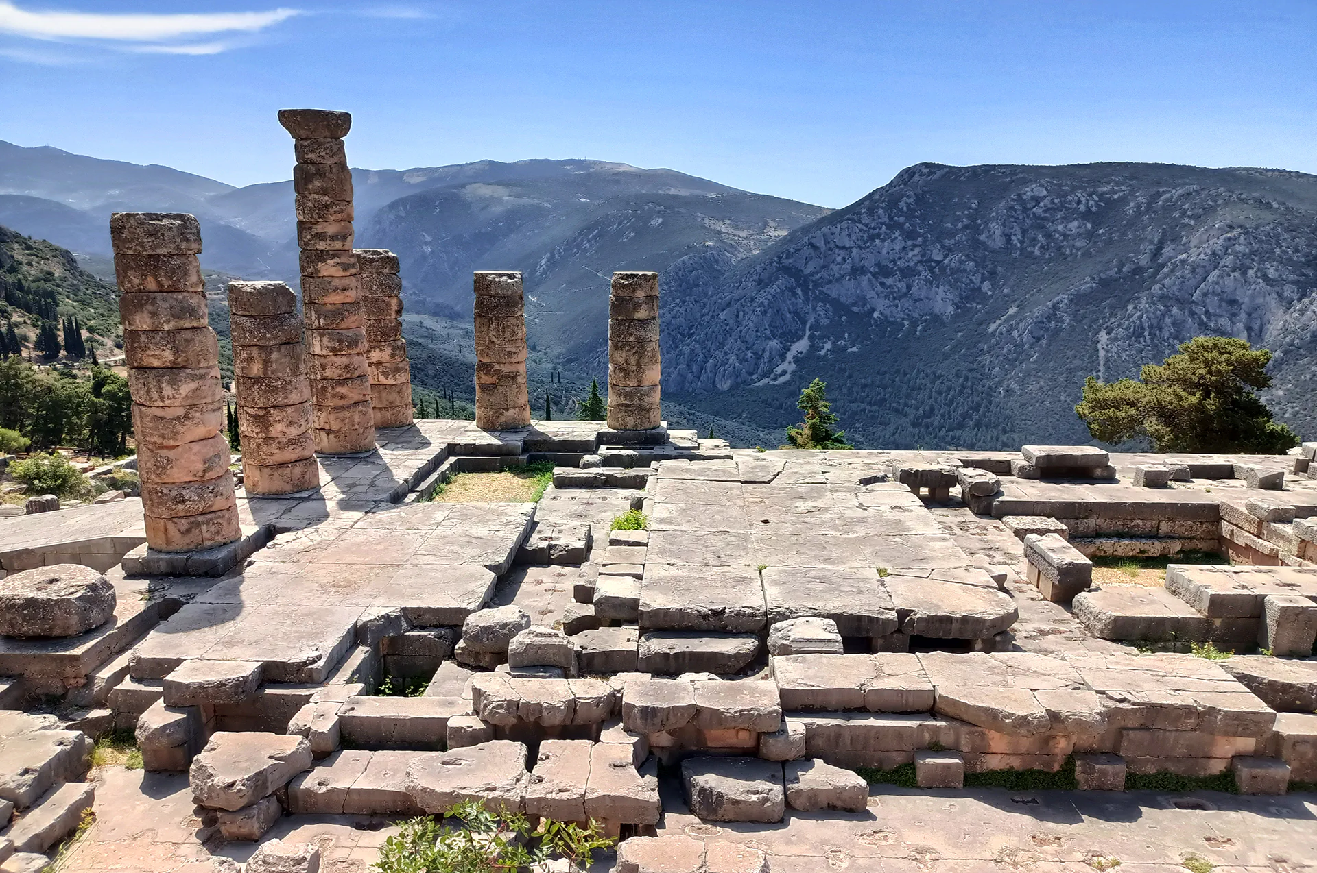 Temple of Apollo ruins in Delphi under clear skies.