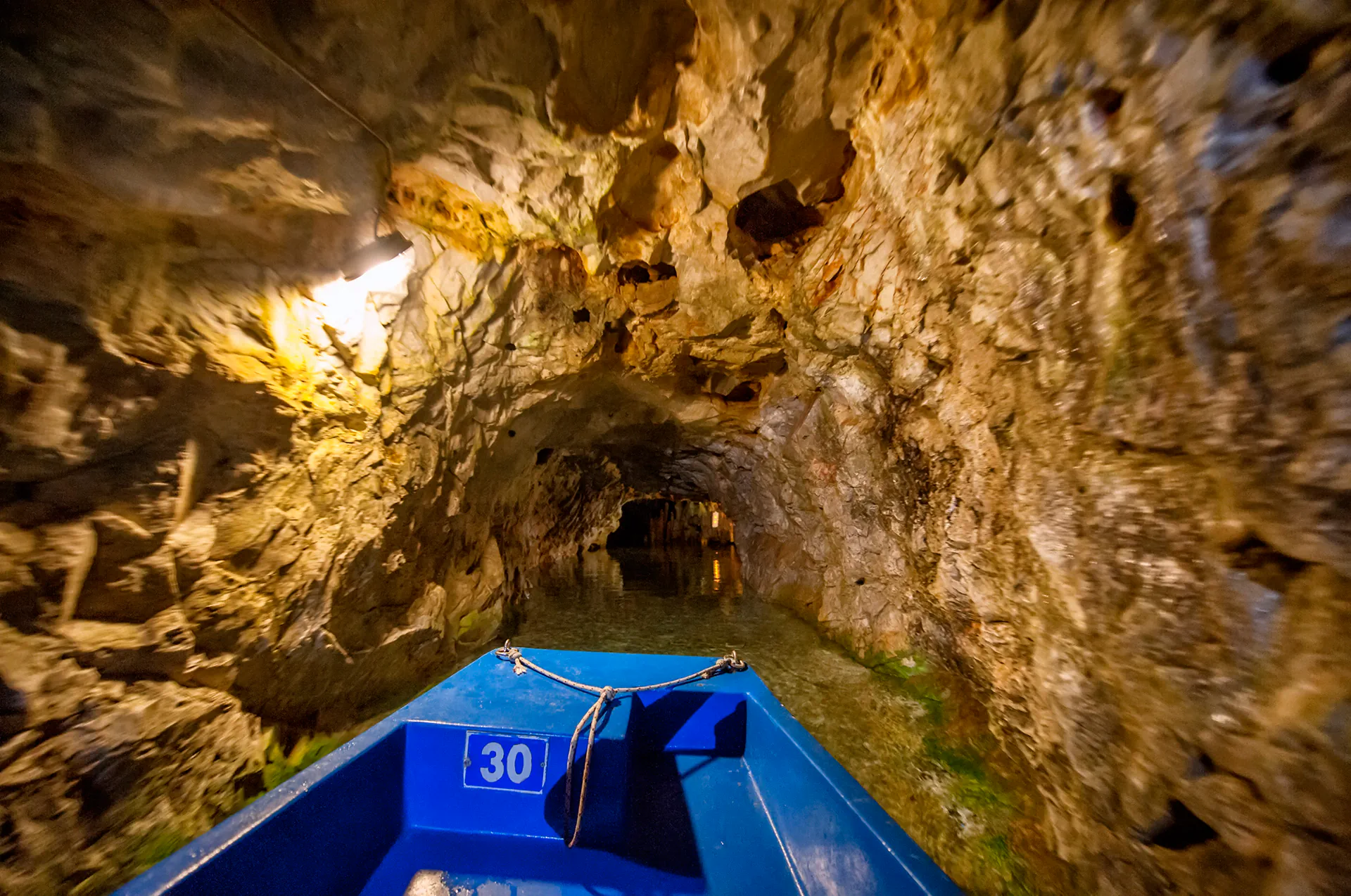 Narrow passage in Diros Caves lit with soft lights.