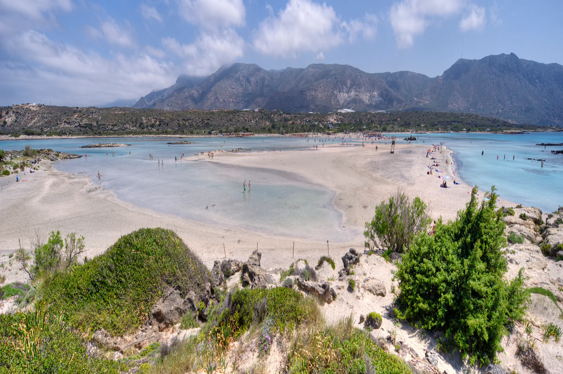 Tourists walking through shallow lagoon waters at Elafonissi.