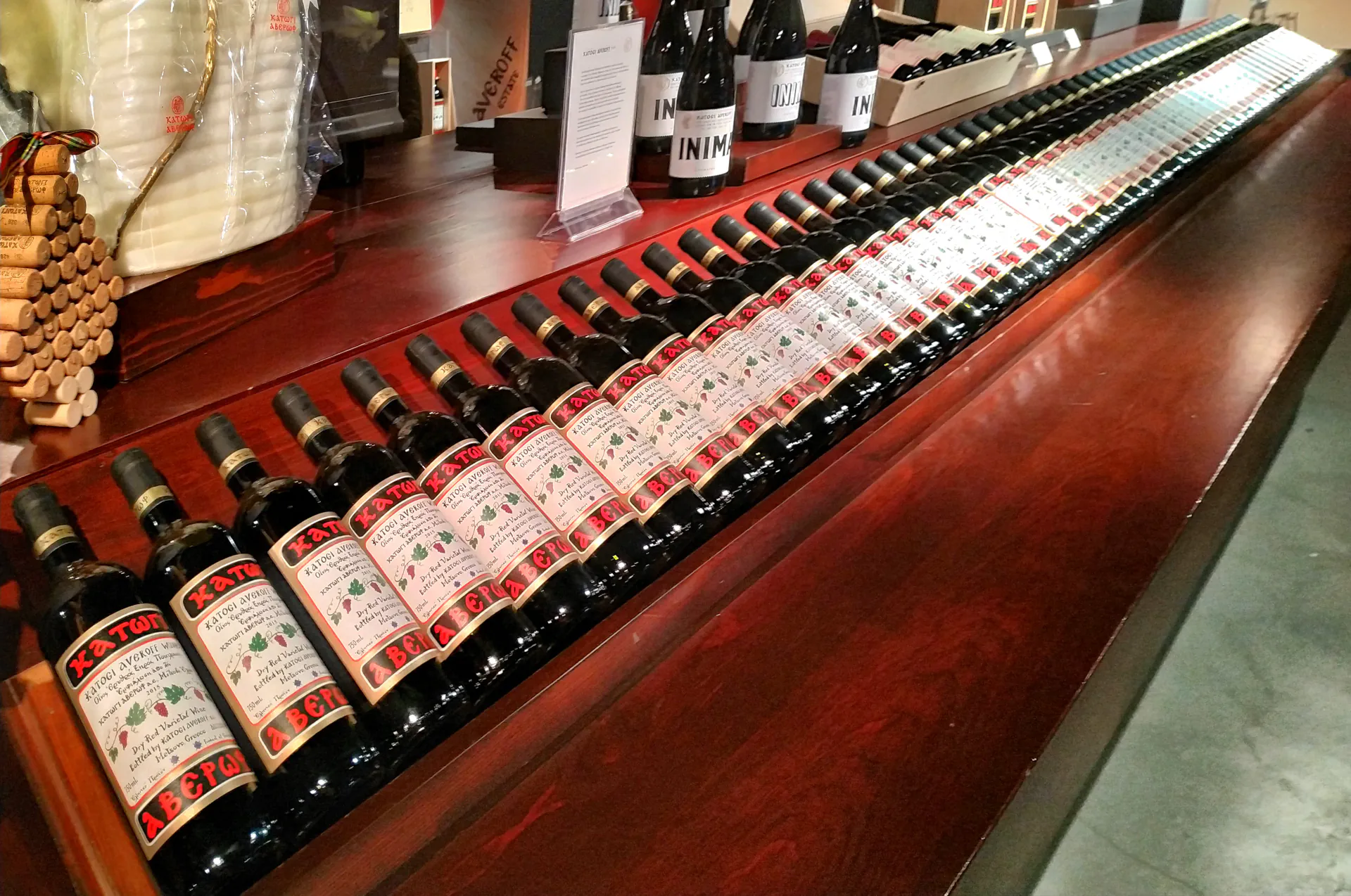 Bottles of Katogi Averoff wine displayed on rustic wooden shelves.
