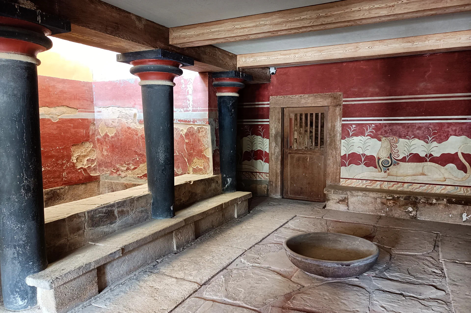 Stone throne with wall frescoes and lustral basin in Knossos palace ruins.
