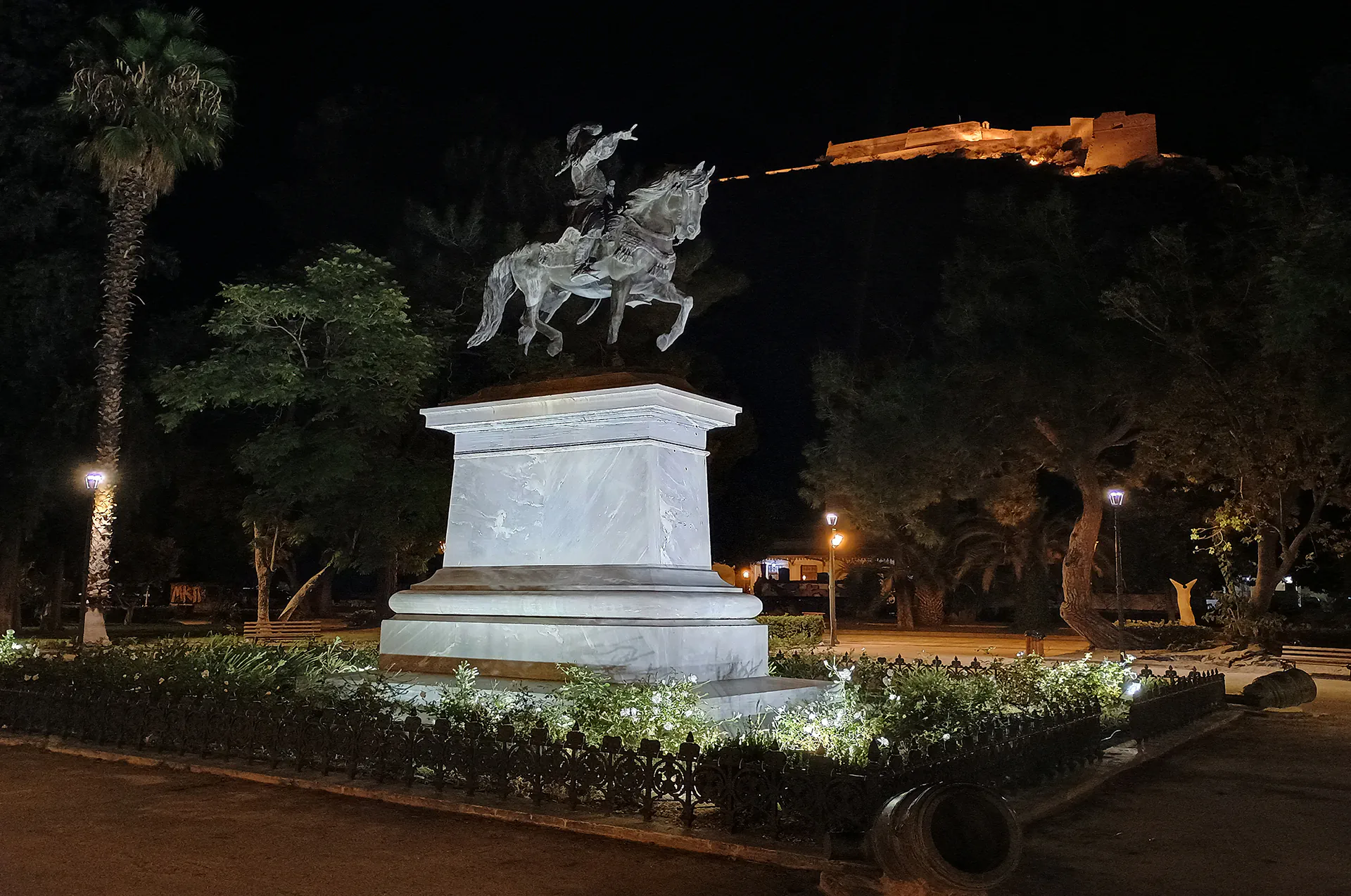 Illuminated statue under a night sky in a town square of Nafplion.