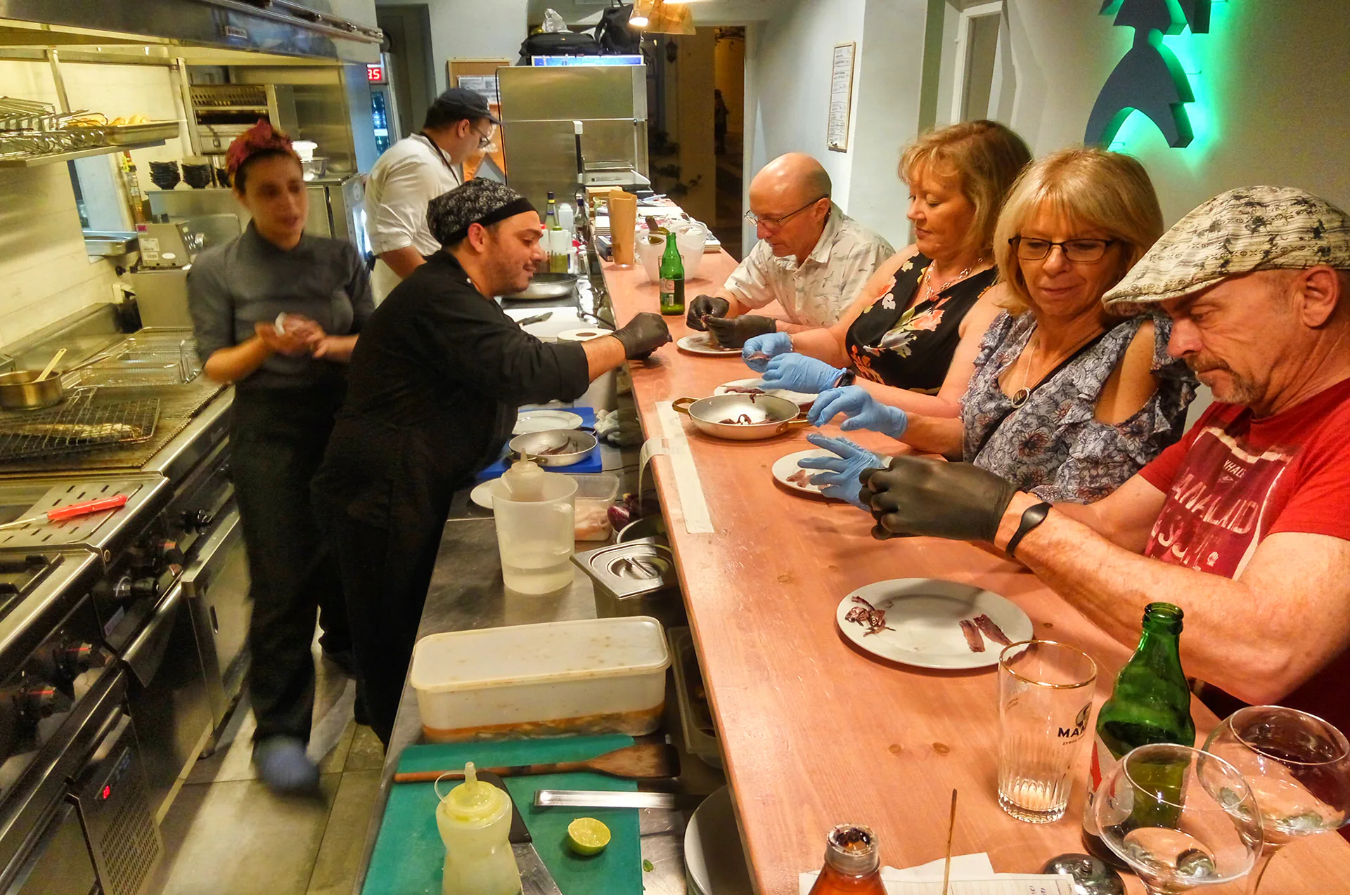 Chef guiding participants in preparing marinated anchovies with olive oil and vinegar in Nafplion.